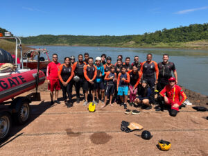 Os bombeiros Marcio Marquetto (à esq.) e Luciano Tristão (à dir.) com o grupo, no atracadouro utilizado para o treinamento, no rio Paraná. Foto: Divulgação.
